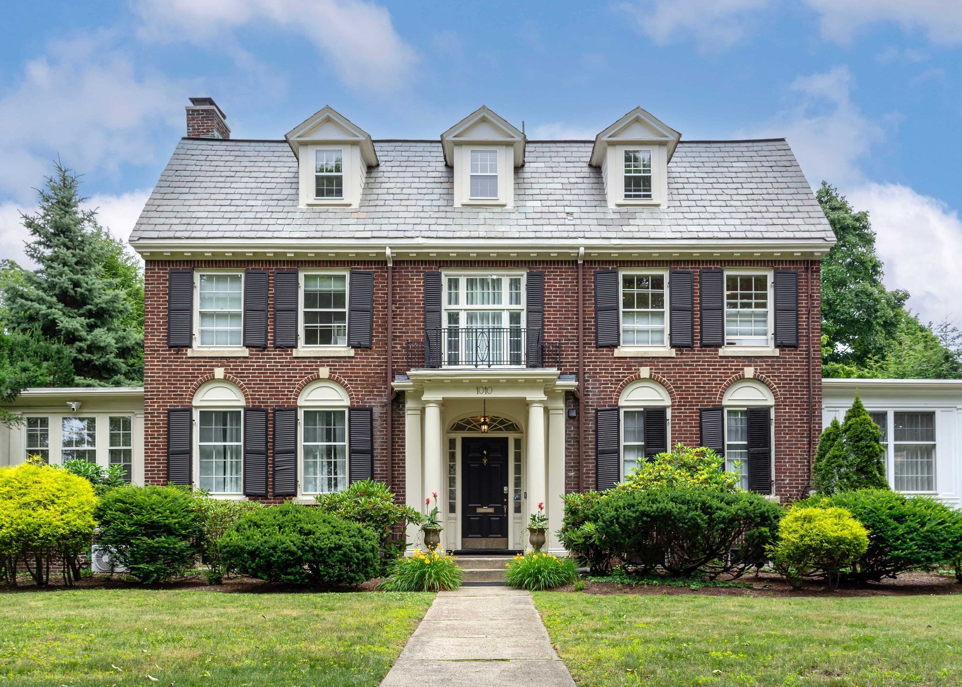 A large brick house with a slate roof and black shutters.