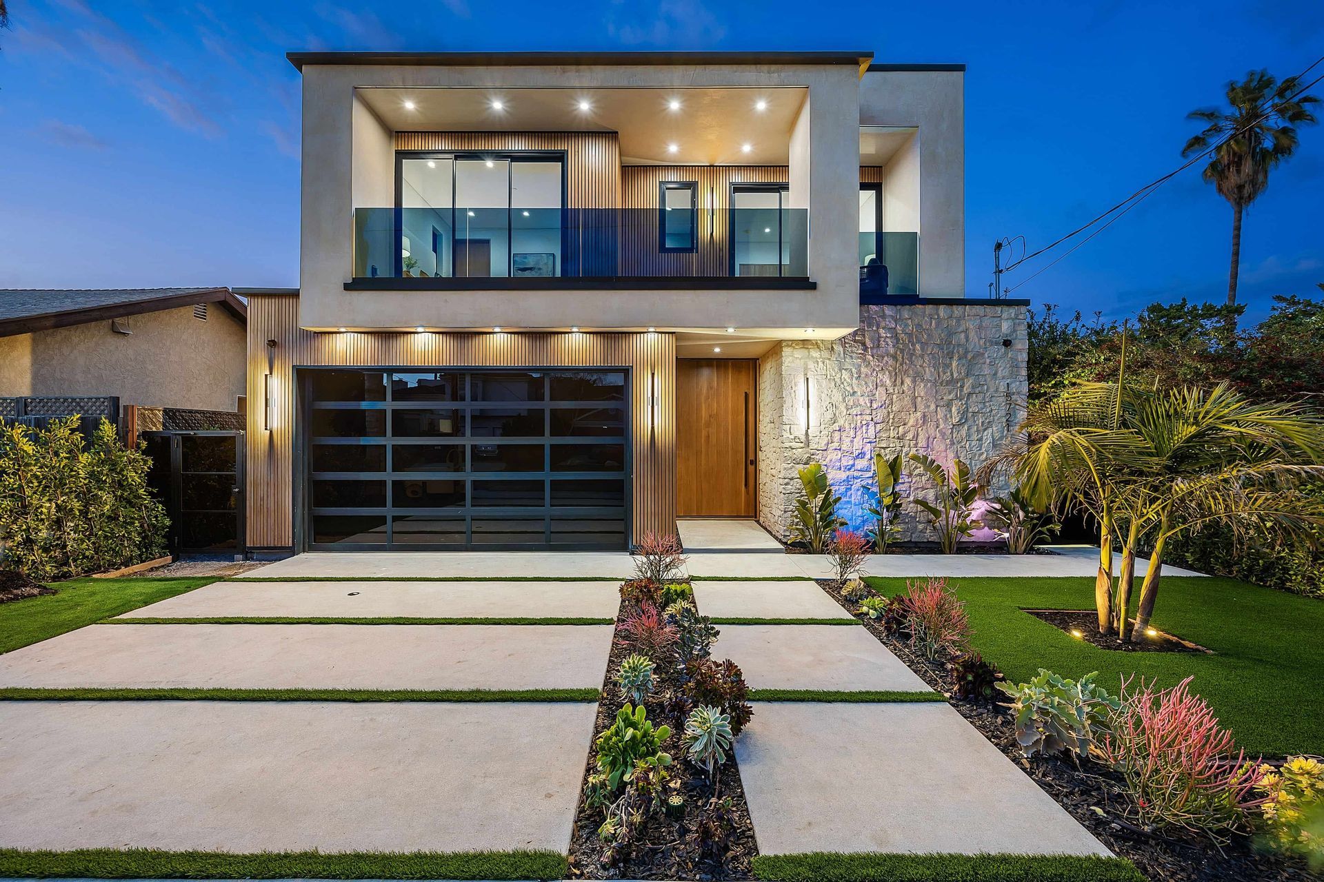 A modern house with a concrete driveway and a glass garage door.