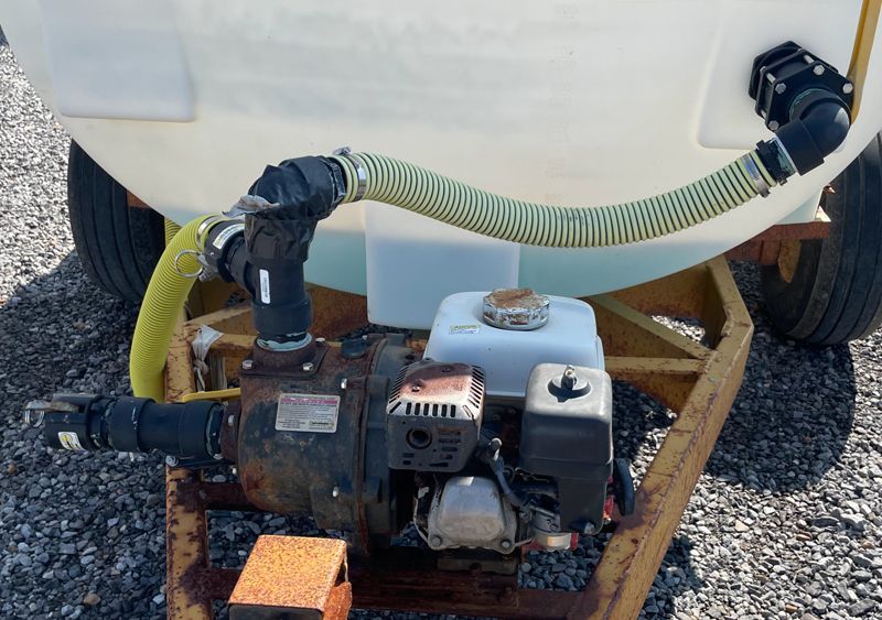 A white tank on a yellow trailer with a pump and Honda engine attached.