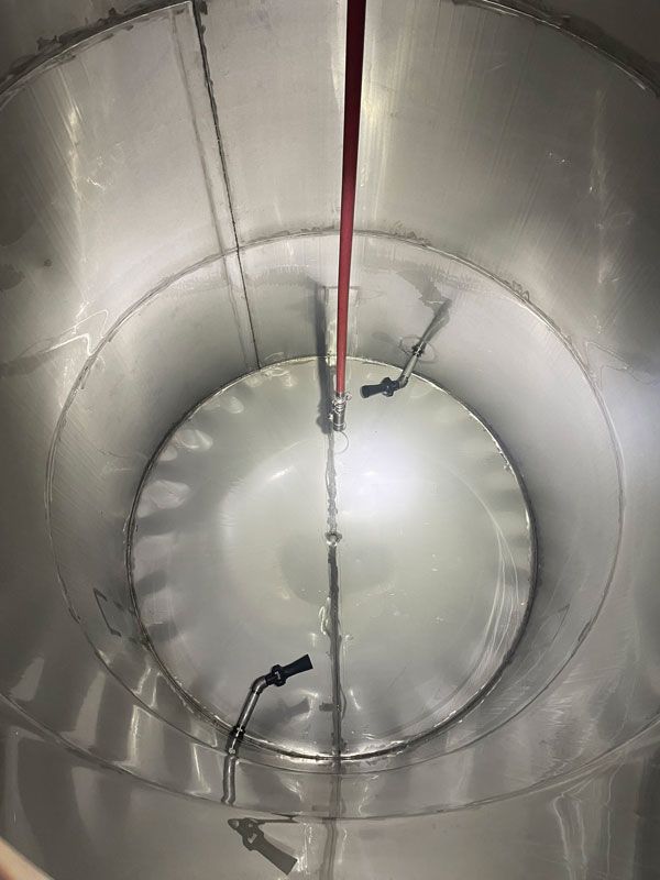 Interior view of a cylindrical metal tank with a central red pipe and attached equipment.