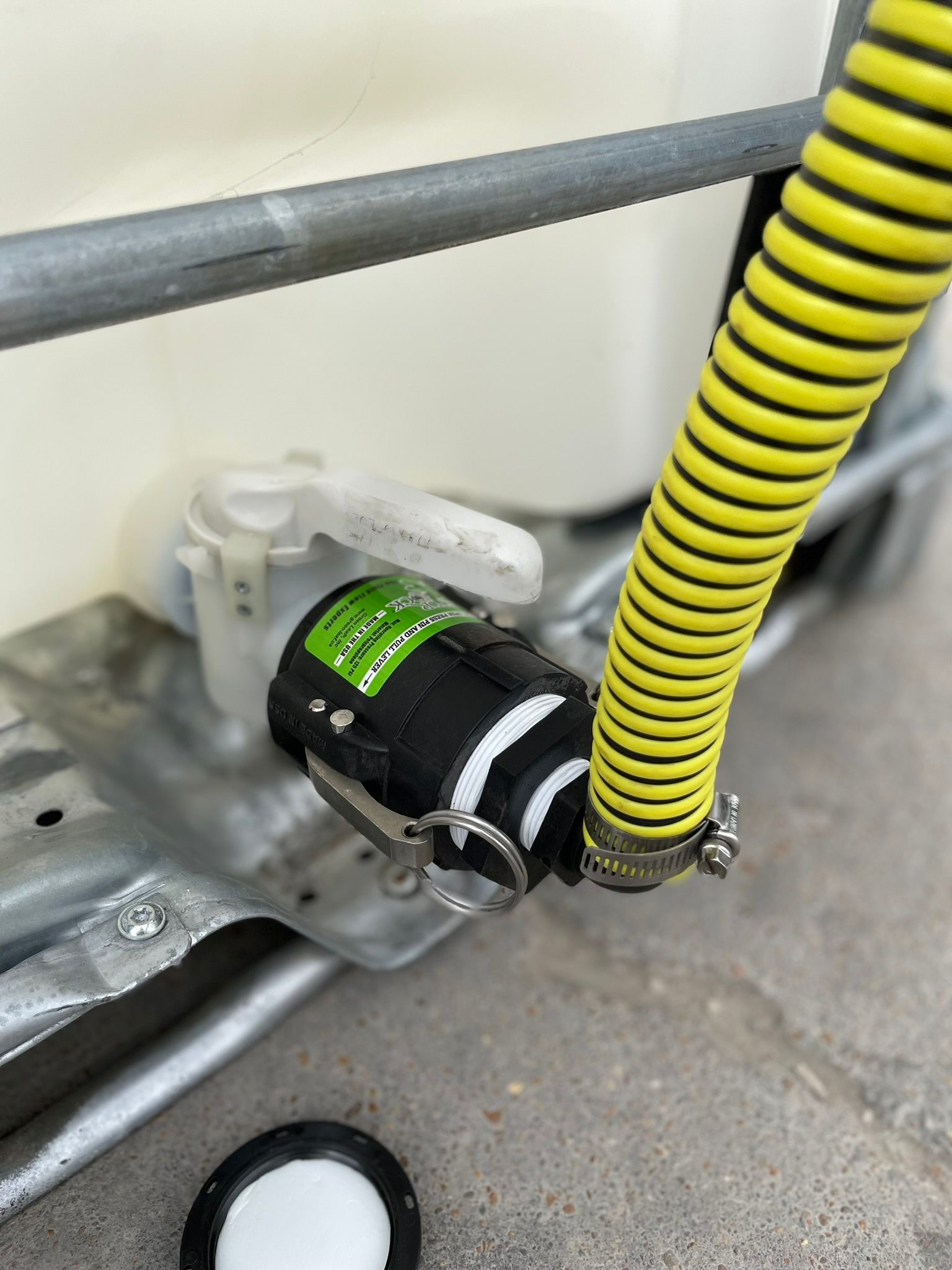 Black and green water filter attached to a tank, with a yellow hose connected.