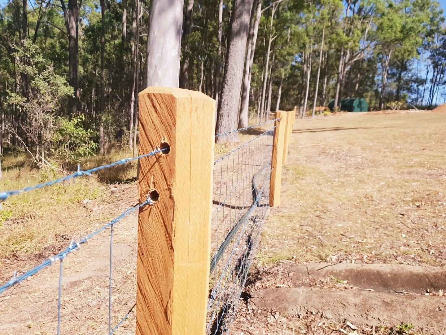 Wooden Fence Posts with Wire Fencing, in A Grassy Field — Sweet's Rural Fencing & Machinery in Lake Macdonald, QLD