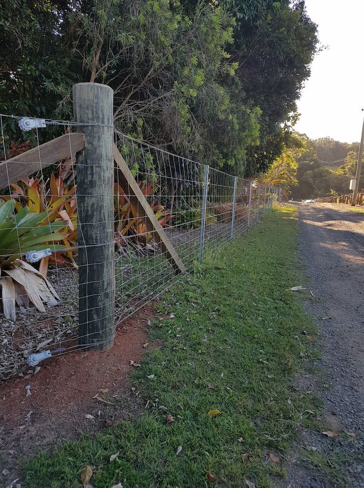 Fence Along a Road With Wood Posts, Wire Mesh, and Grass — Sweet's Rural Fencing & Machinery in Lake Macdonald, QLD