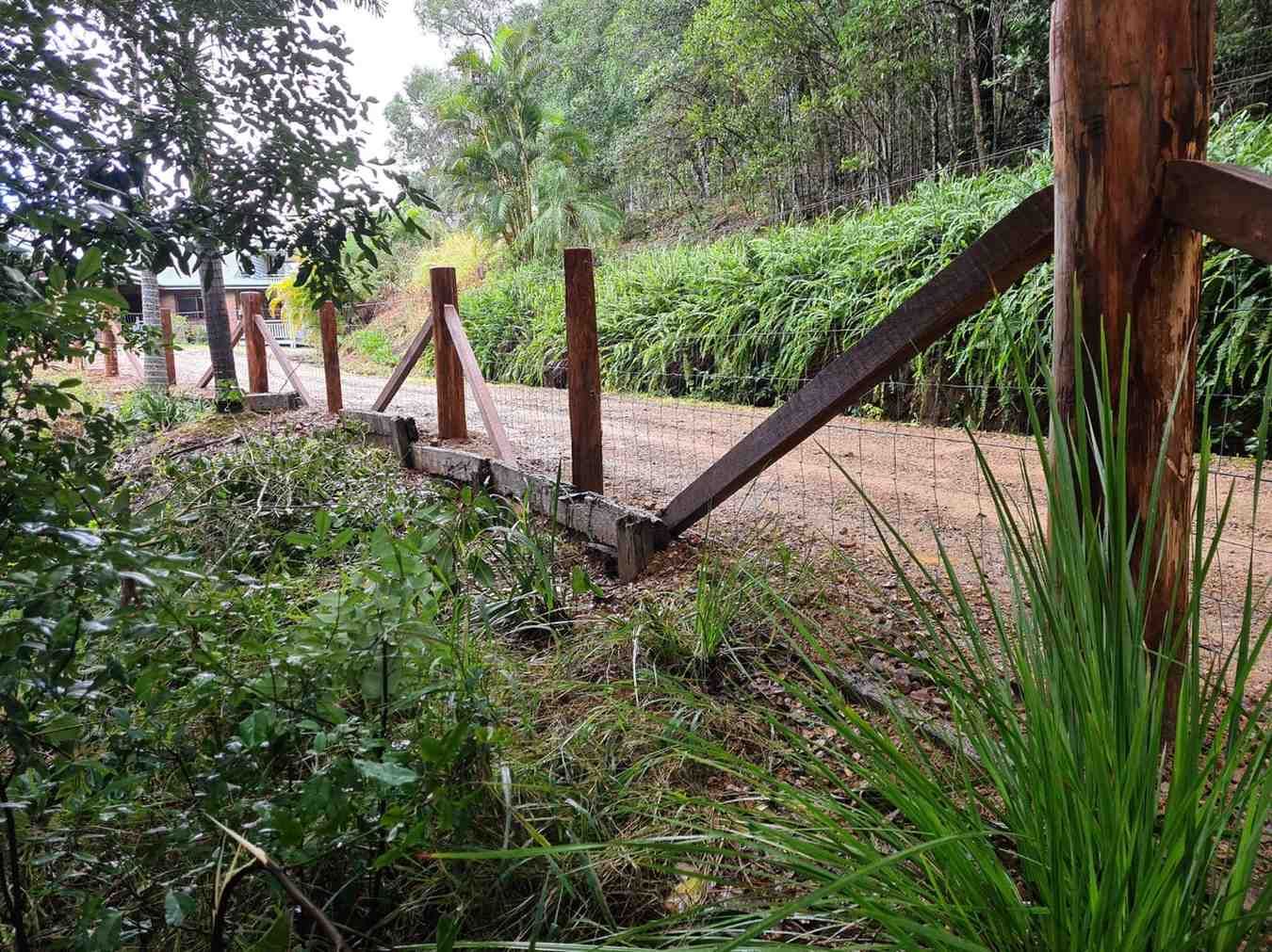 Wooden Fence Alongside a Dirt Path in A Green, Natural Setting — Sweet's Rural Fencing & Machinery in Lake Macdonald, QLD