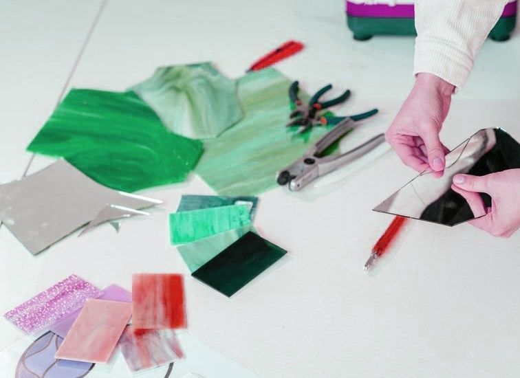 A Person Is Cutting A Piece Of Glass With A Pair Of Scissors — Townsville Stained Glass In Charters Towers, QLD