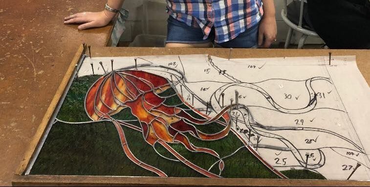 A Woman Is Standing Next To A Stained Glass Painting Of A Jellyfish — Townsville Stained Glass In Townsville, QLD