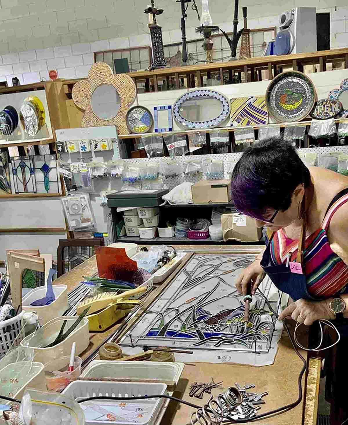 A Woman Is Working On A Stained Glass Window In A Workshop — Townsville Stained Glass In Aitkenvale, QLD