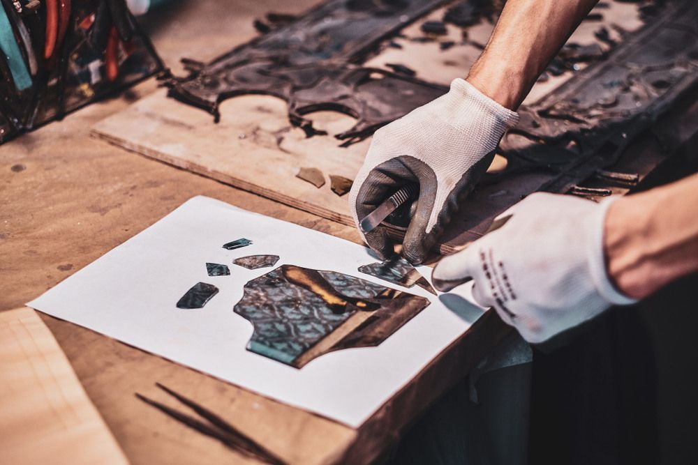 A Person Is Cutting A Piece Of Glass On A Piece Of Paper — Townsville Stained Glass In Mackay, QLD