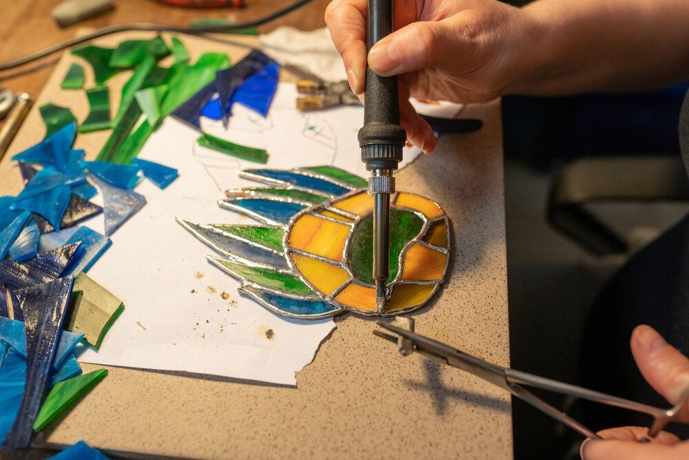 A Person Is Making A Stained Glass Window With A Soldering Iron — Townsville Stained Glass In Mackay, QLD