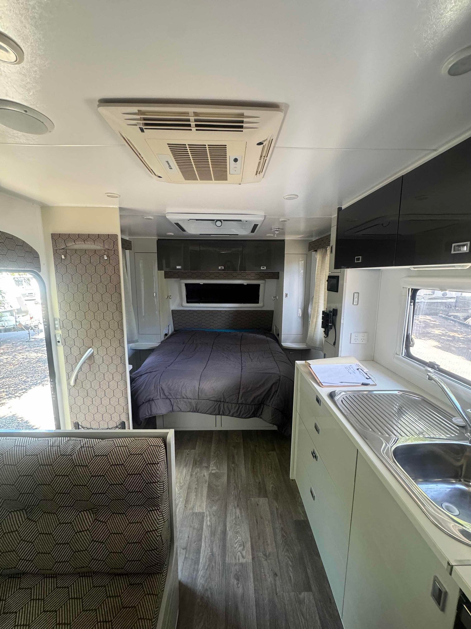 A Gray and White Interior With a Bed, Kitchen and Overhead Air Conditioning — B & C Caravan Service Pty Ltd In Dubbo, NSW