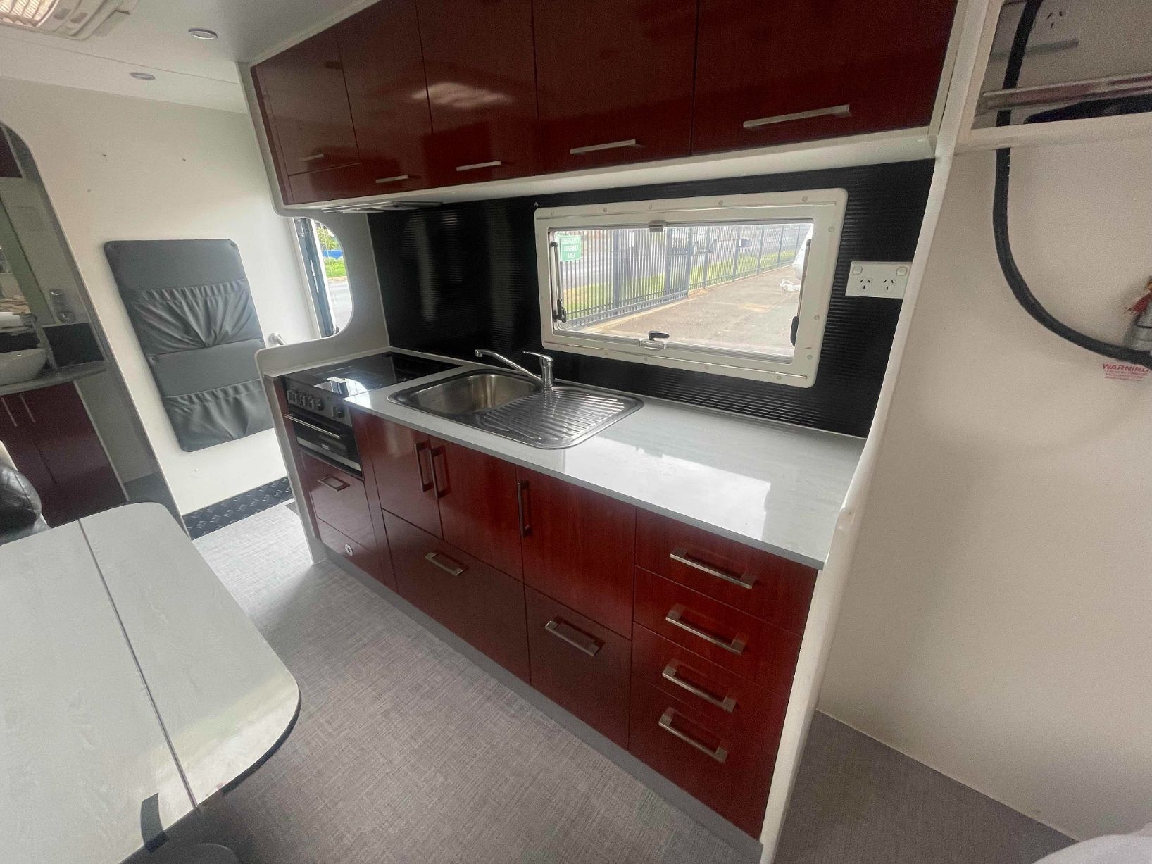 A Kitchen in a Camper With a Stove, Sink, and Bed — B & C Caravan Service Pty Ltd In Dubbo, NSW