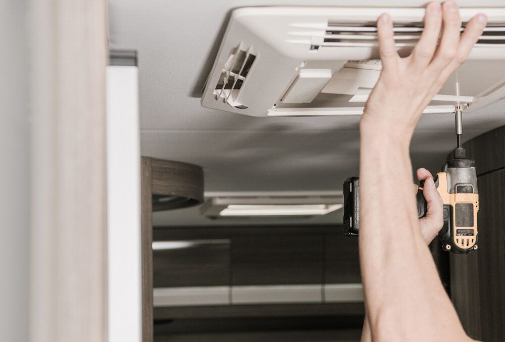 A Person is Fixing a Ceiling Fan With a Drill — B & C Caravan Service Pty Ltd In Dubbo, NSW