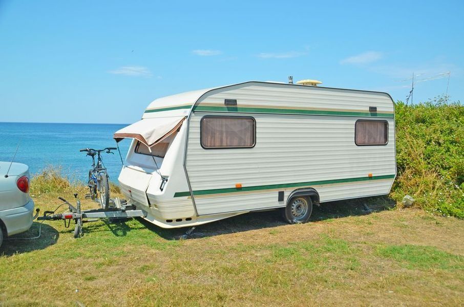 A Caravan is Parked in a Grassy Field Next to the Ocean — B & C Caravan Service Pty Ltd In Dubbo, NSW