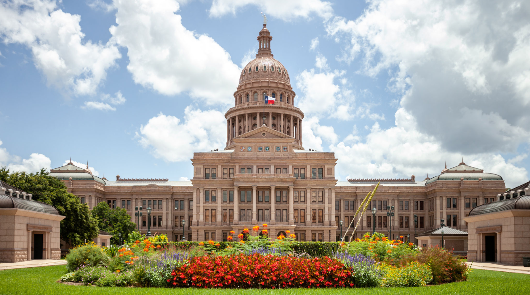 A large building with a dome and flowers in front of it.