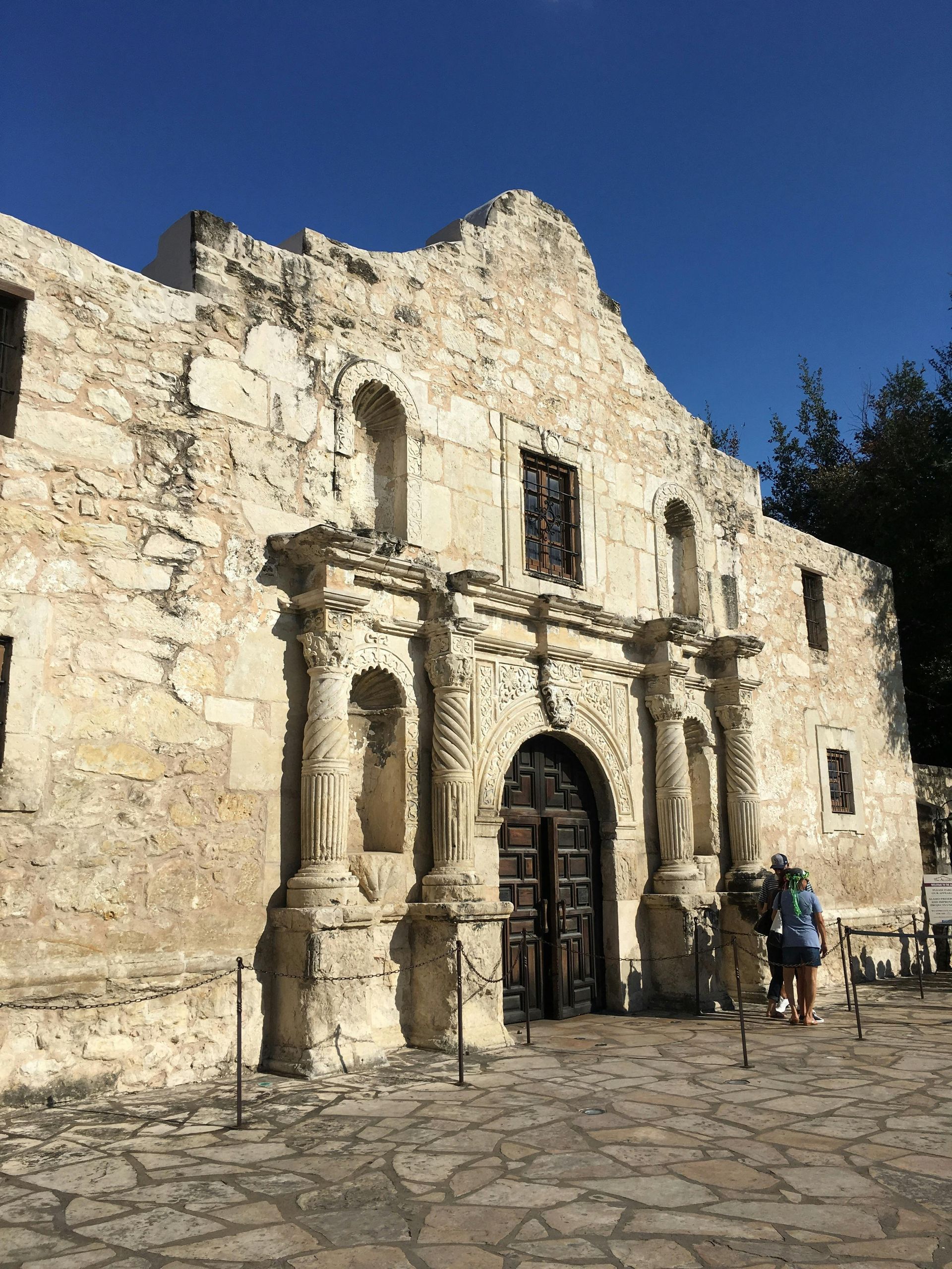 A group of people are standing in front of an old stone building.