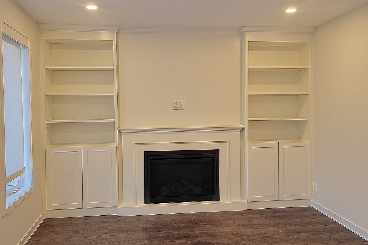 Des étagères blanches intégrées encadrent une cheminée dans un salon.