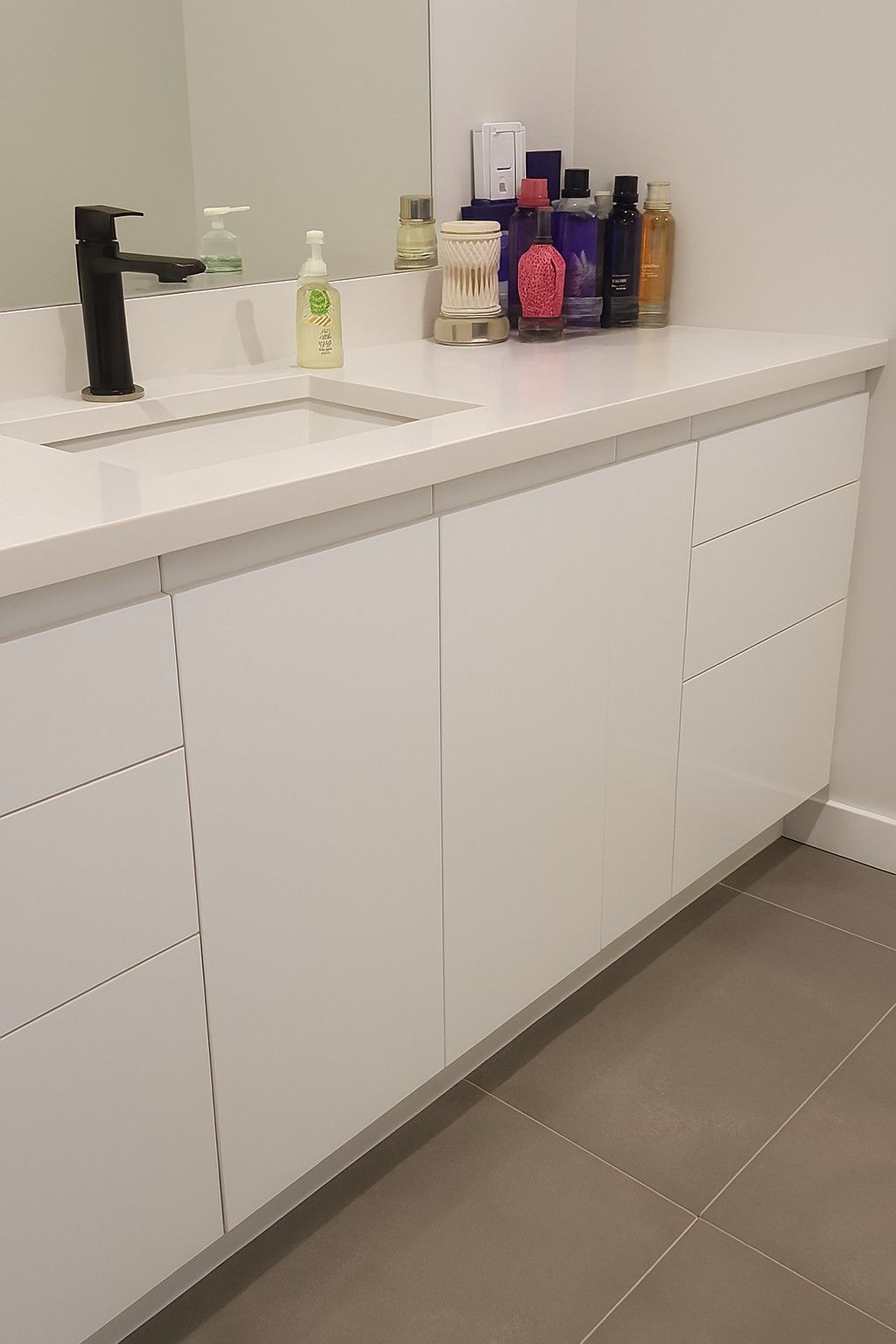 Meuble-lavabo blanc avec robinet noir, articles de toilette sur le comptoir.