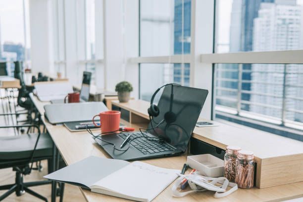 A desk with a laptop and headphones on it in an office