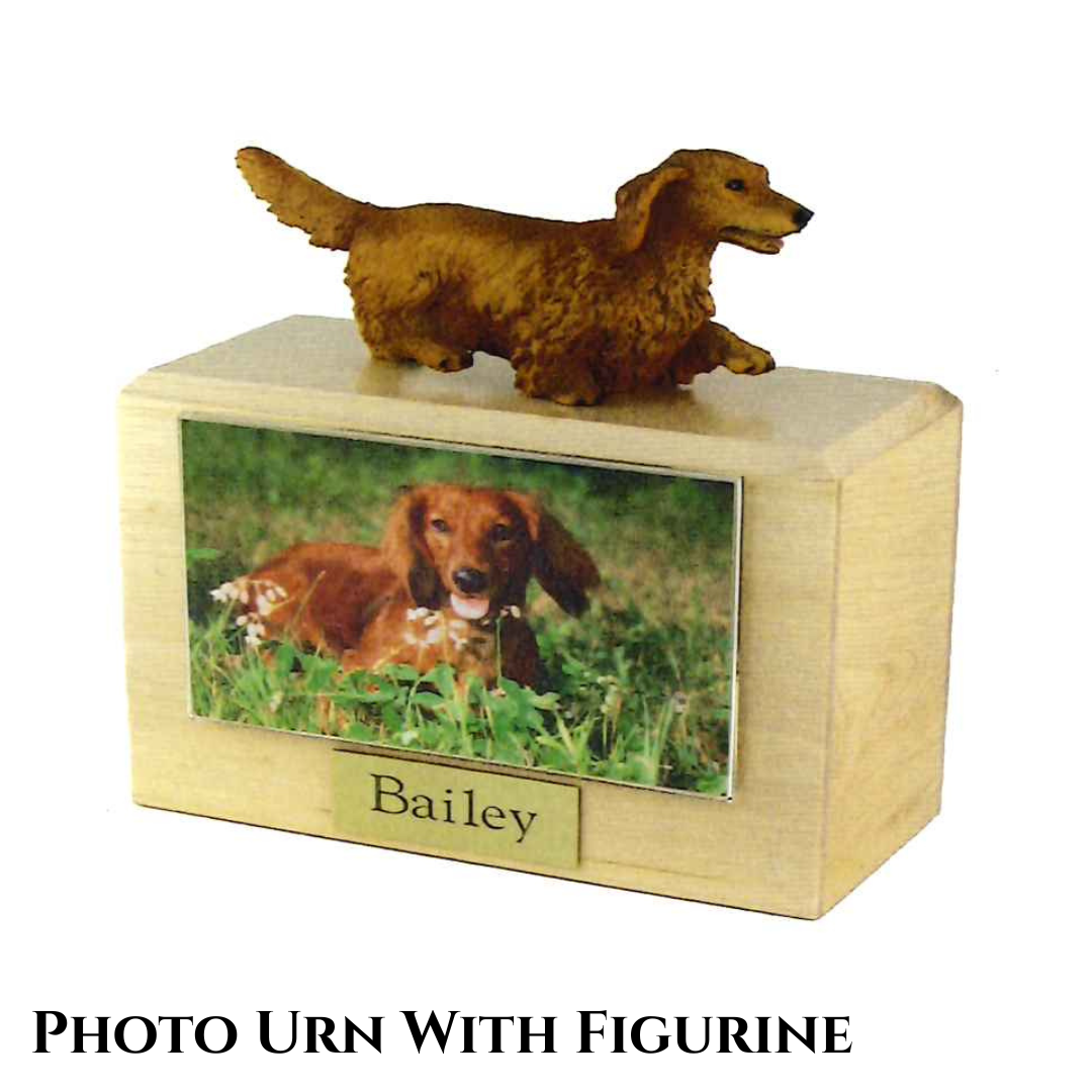 A wooden urn with a dog figurine on top and a photo and engraved nameplate on the front.