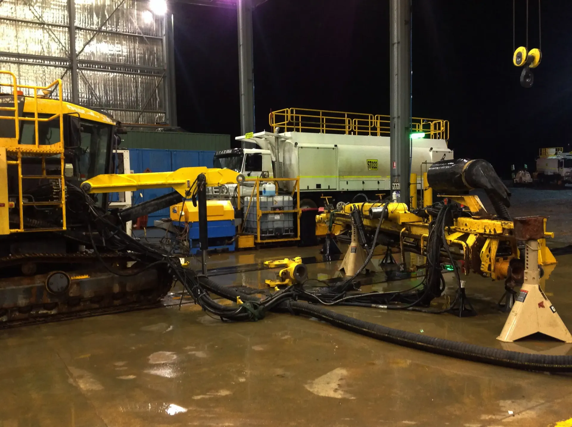 A yellow tractor is parked next to a white truck.