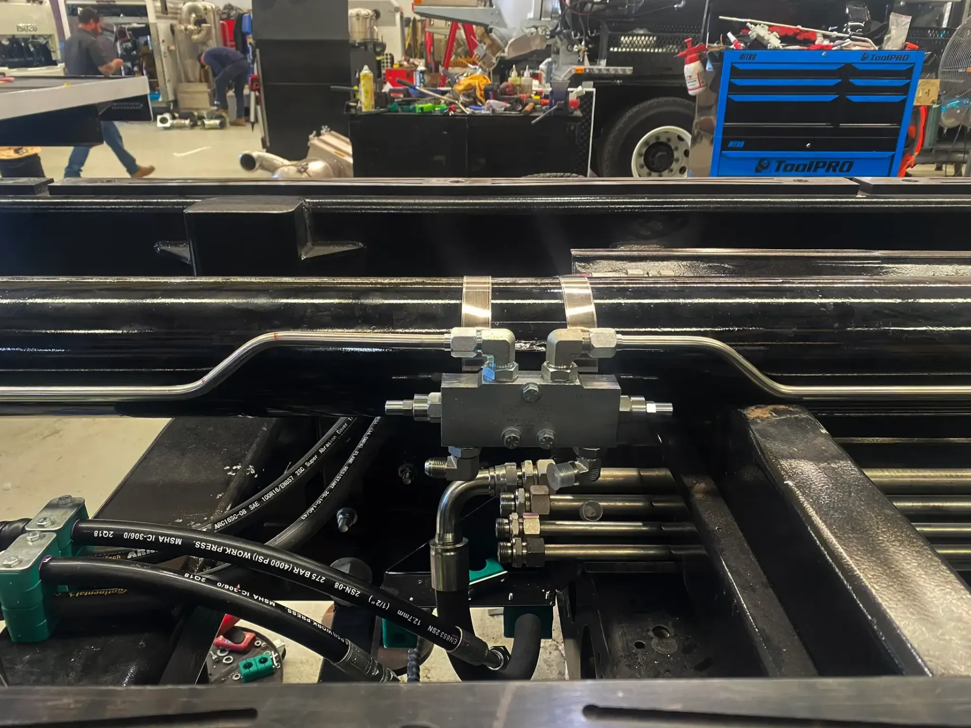 A hydraulic system is being installed on a truck in a factory