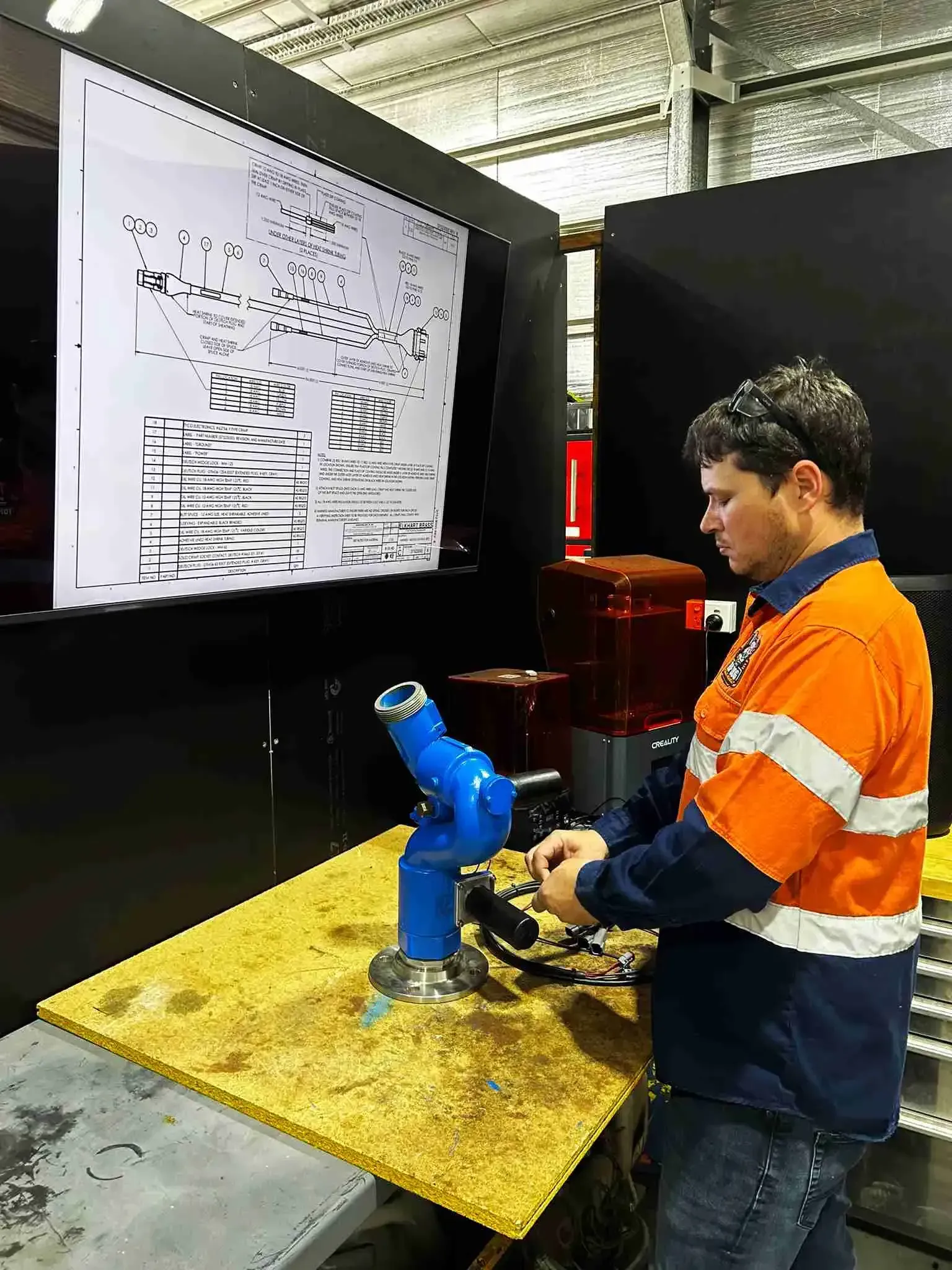 A man is working on a robotic arm in a factory.