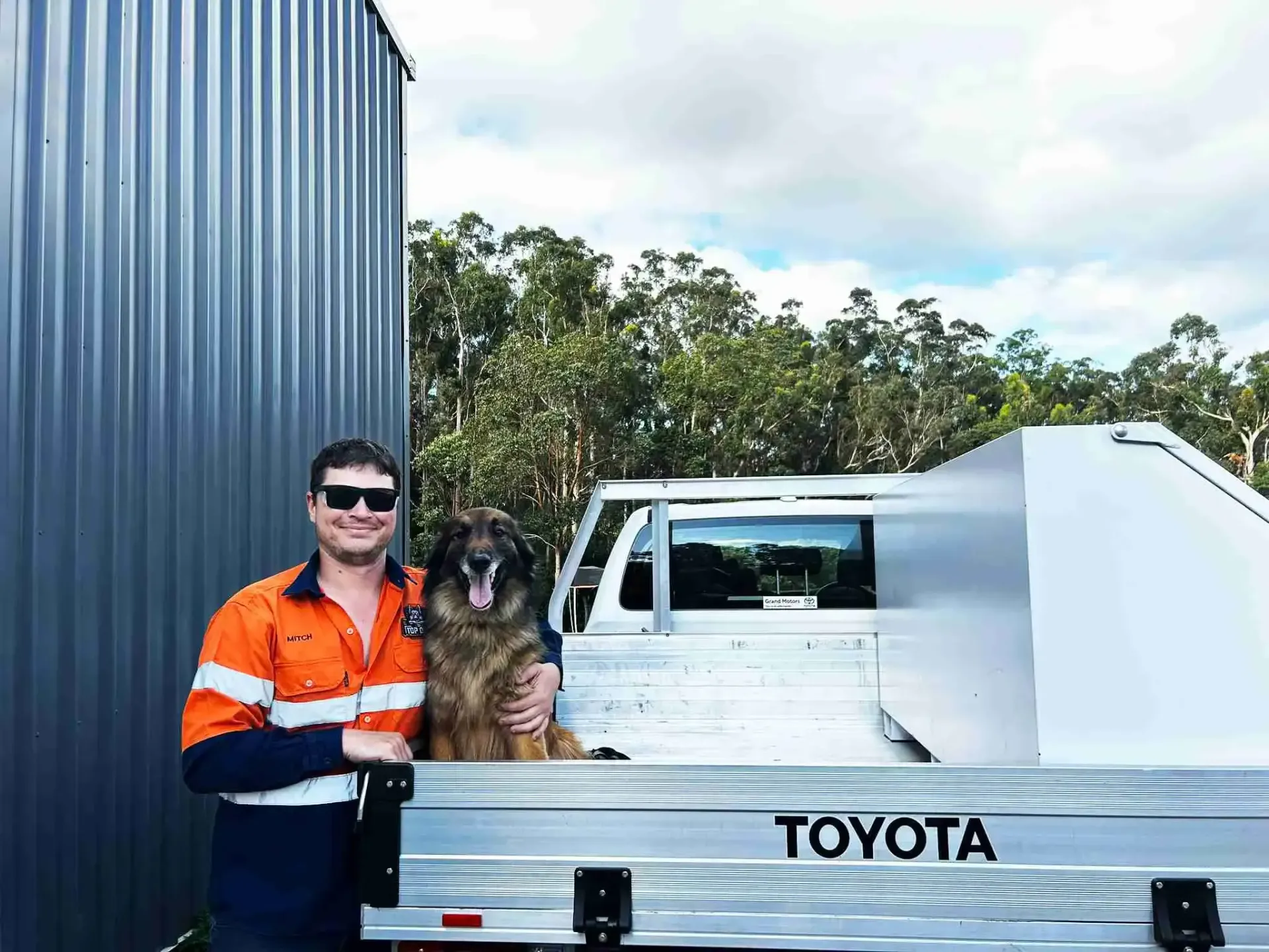 A man and a dog are standing next to a toyota truck.