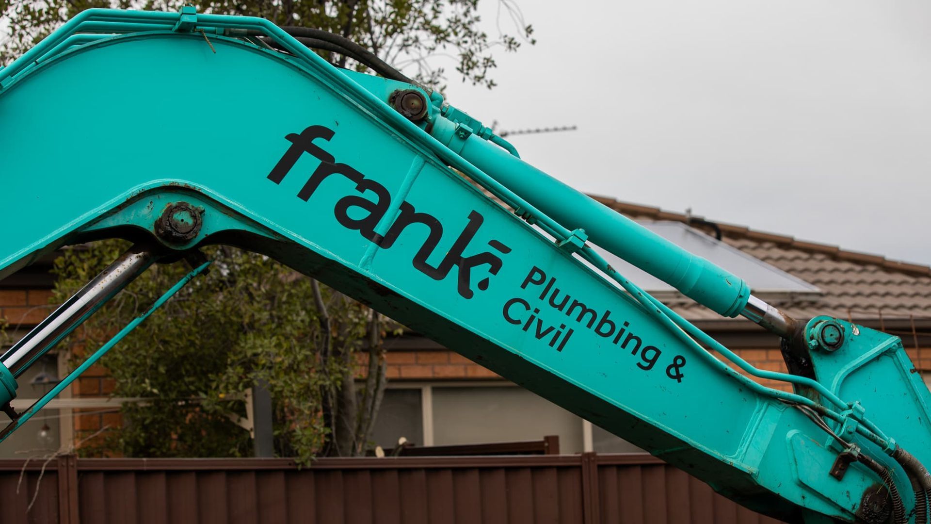 A Green Excavator With The Words Frank Plumbing And Civil Written On It — Frank Plumbing In Delacombe, VIC