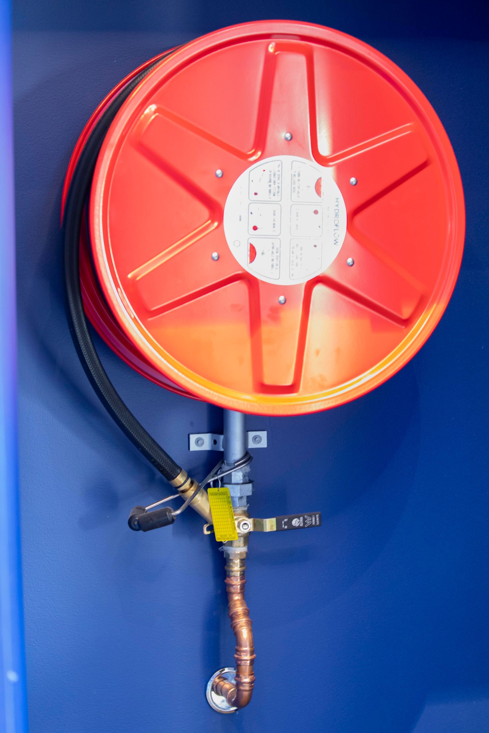 Fire hose against a very blue wall— Frank Plumbing In Delacombe, VIC