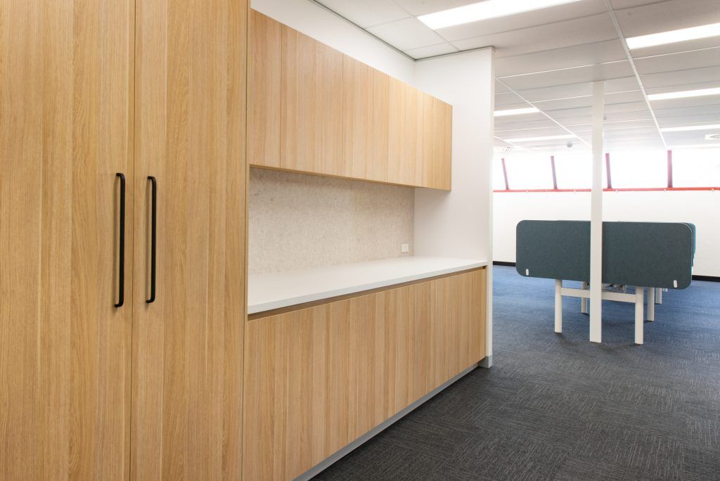 A Kitchen In An Office With Wooden Cabinets And A Table — Frank Plumbing In Delacombe, VIC