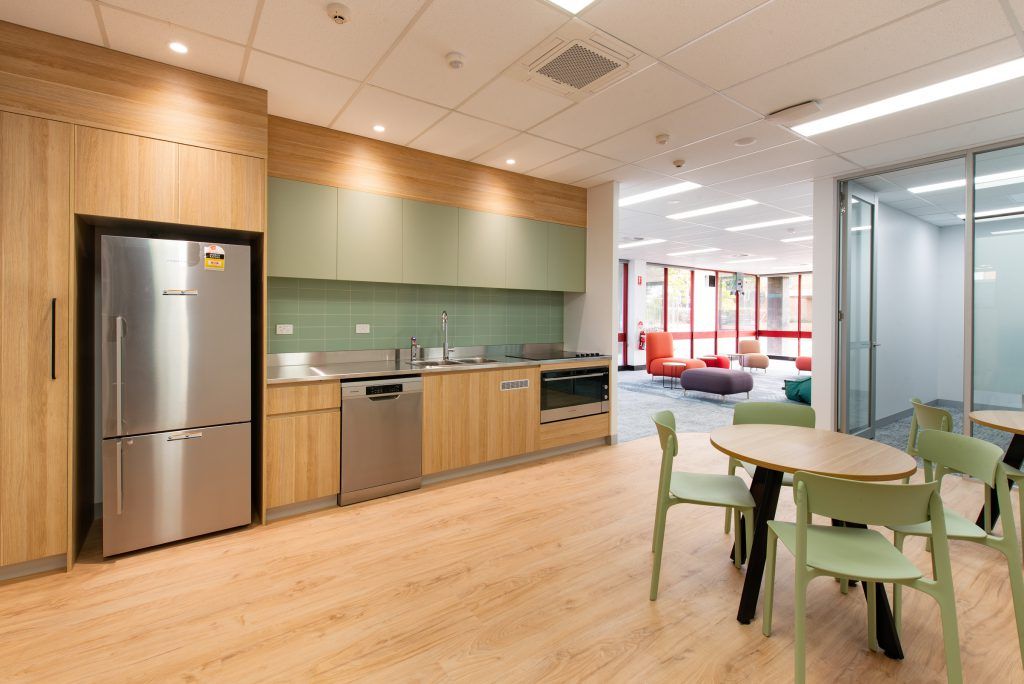 A Kitchen With Stainless Steel Appliances , Wooden Cabinets , Tables And Chairs — Frank Plumbing In Delacombe, VIC