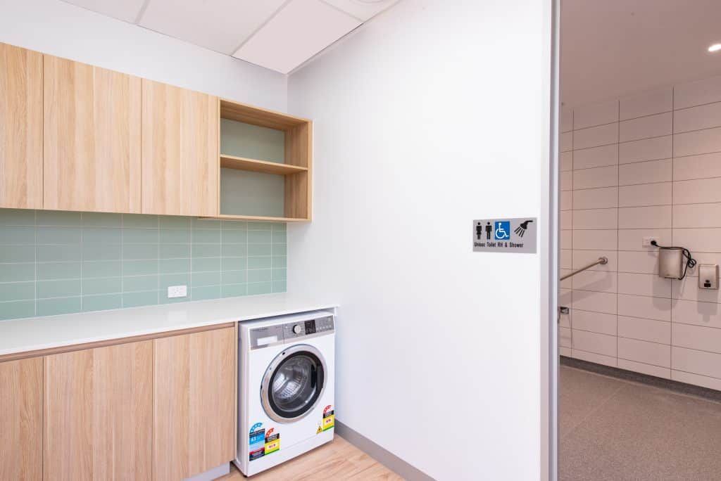 A Laundry Room With A Washing Machine And Wooden Cabinets — Frank Plumbing In Delacombe, VIC