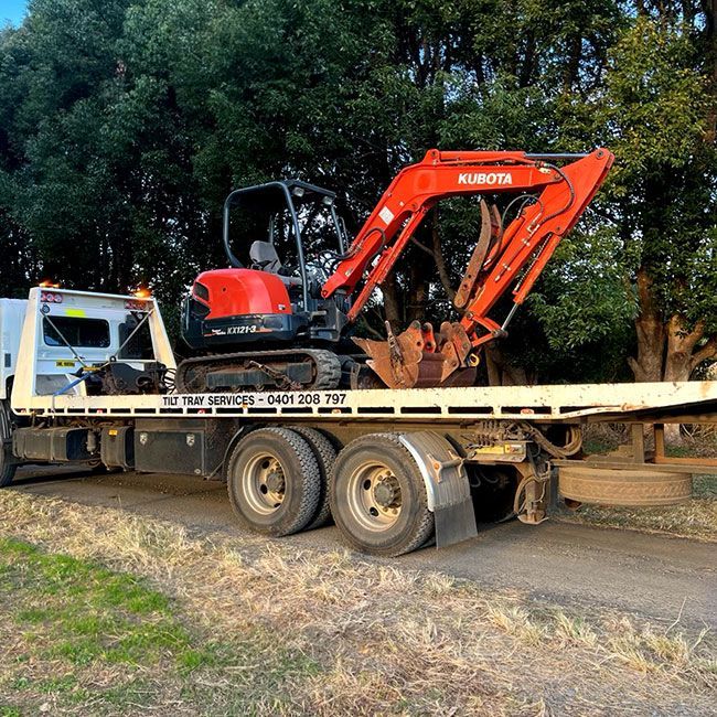 A Red Kubota Excavator is Sitting on Top of a Flatbed Tow Truck — Tallow Tree Services Pty Ltd in Bangalow, NSW