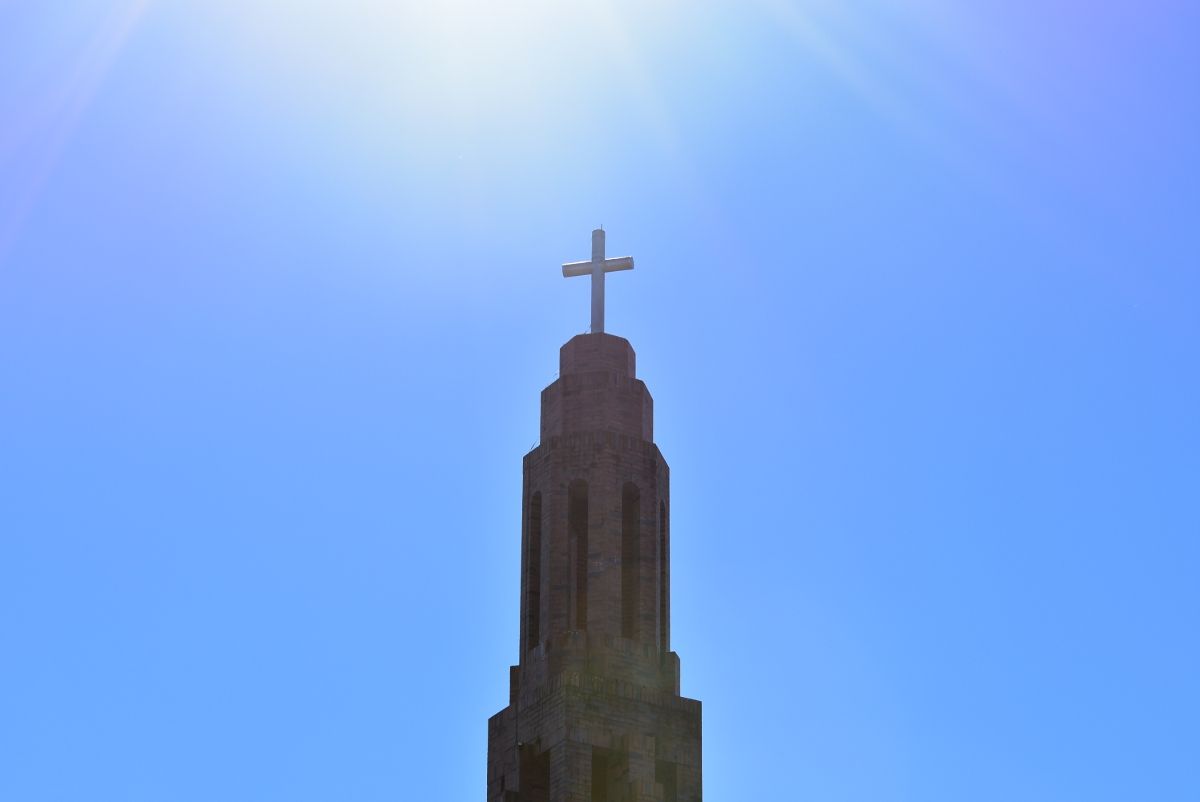 A Church Tower With a Cross on Top of It Against a Blue Sky — Tallow Tree Services Pty Ltd in Casino, NSW