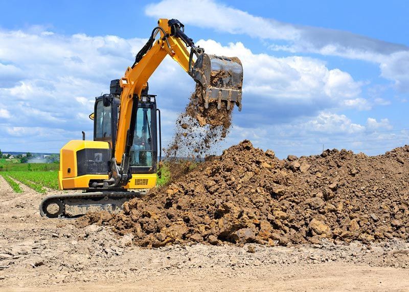 A Yellow Excavator is Digging a Pile of Dirt — Tallow Tree Services Pty Ltd in Tweed Heads, NSW