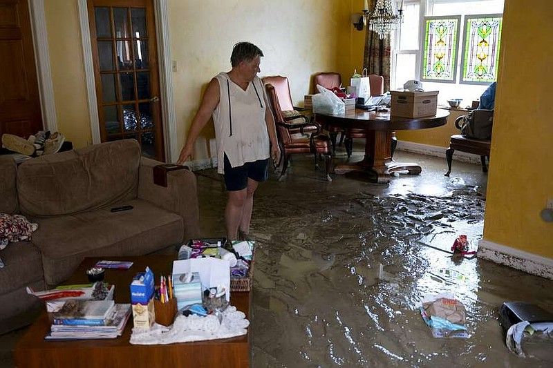 A woman is standing in a flooded living room.