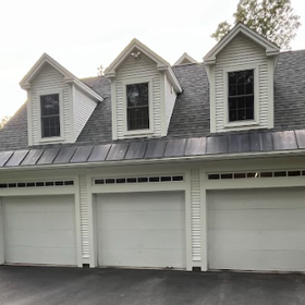 White three-car garage with three dormers, black roof, and dark driveway.