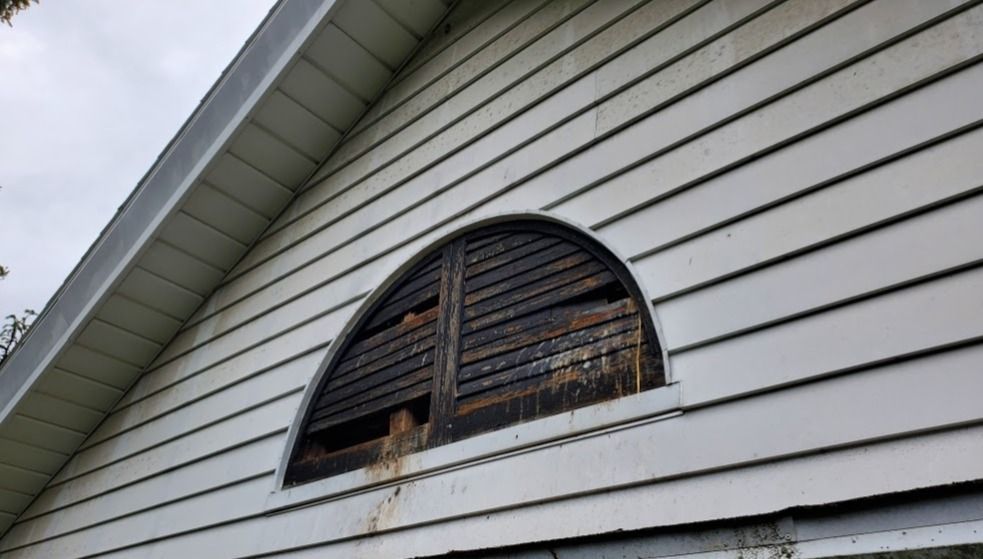 A white house with a window with shutters on it.