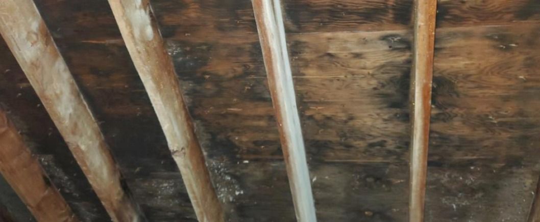 A close up of a ceiling with wooden beams and a pipe.