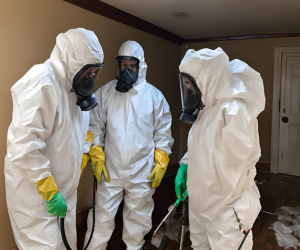 A group of people wearing protective suits and gas masks