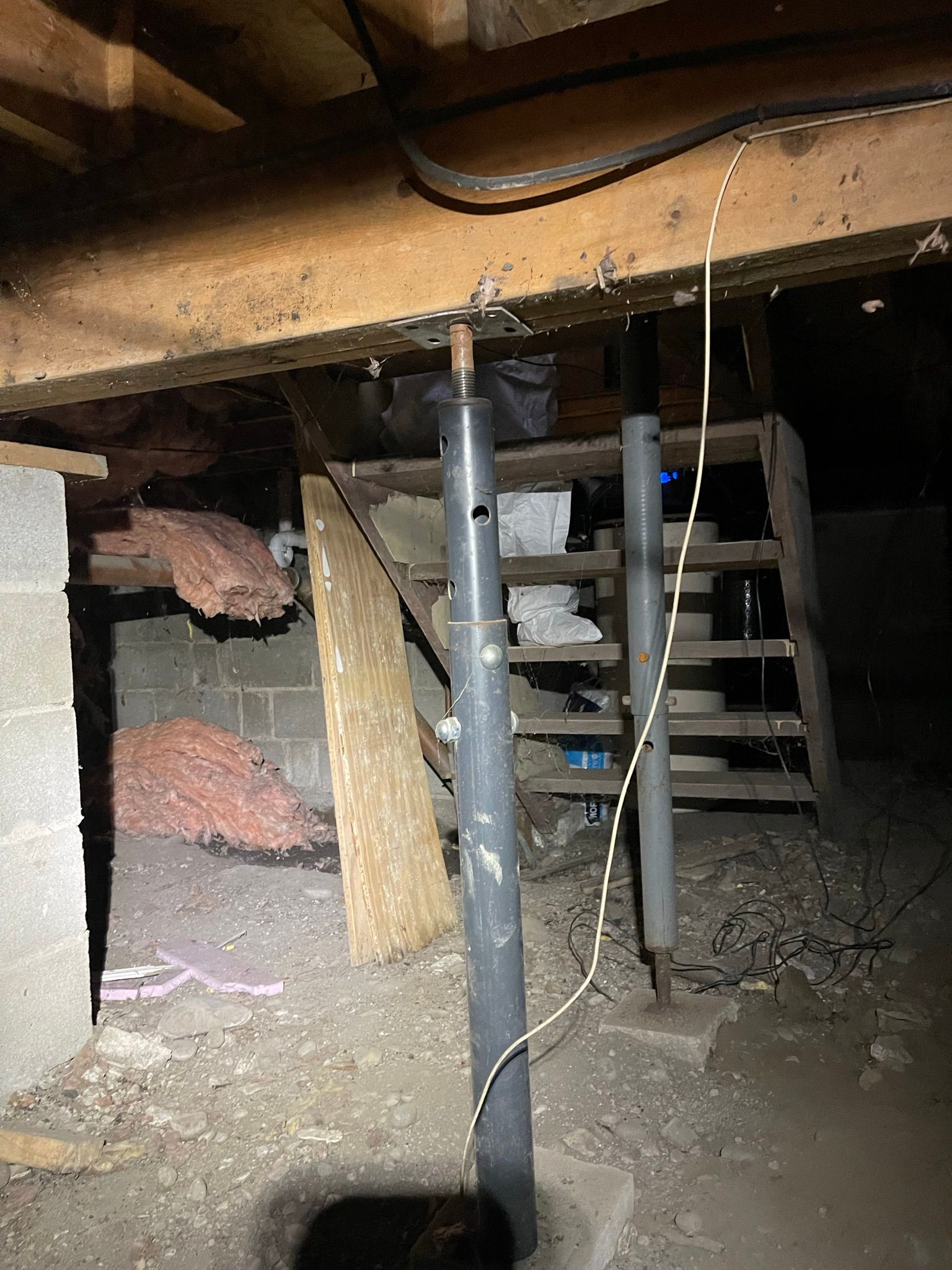 A basement with a pipe and stairs in it.