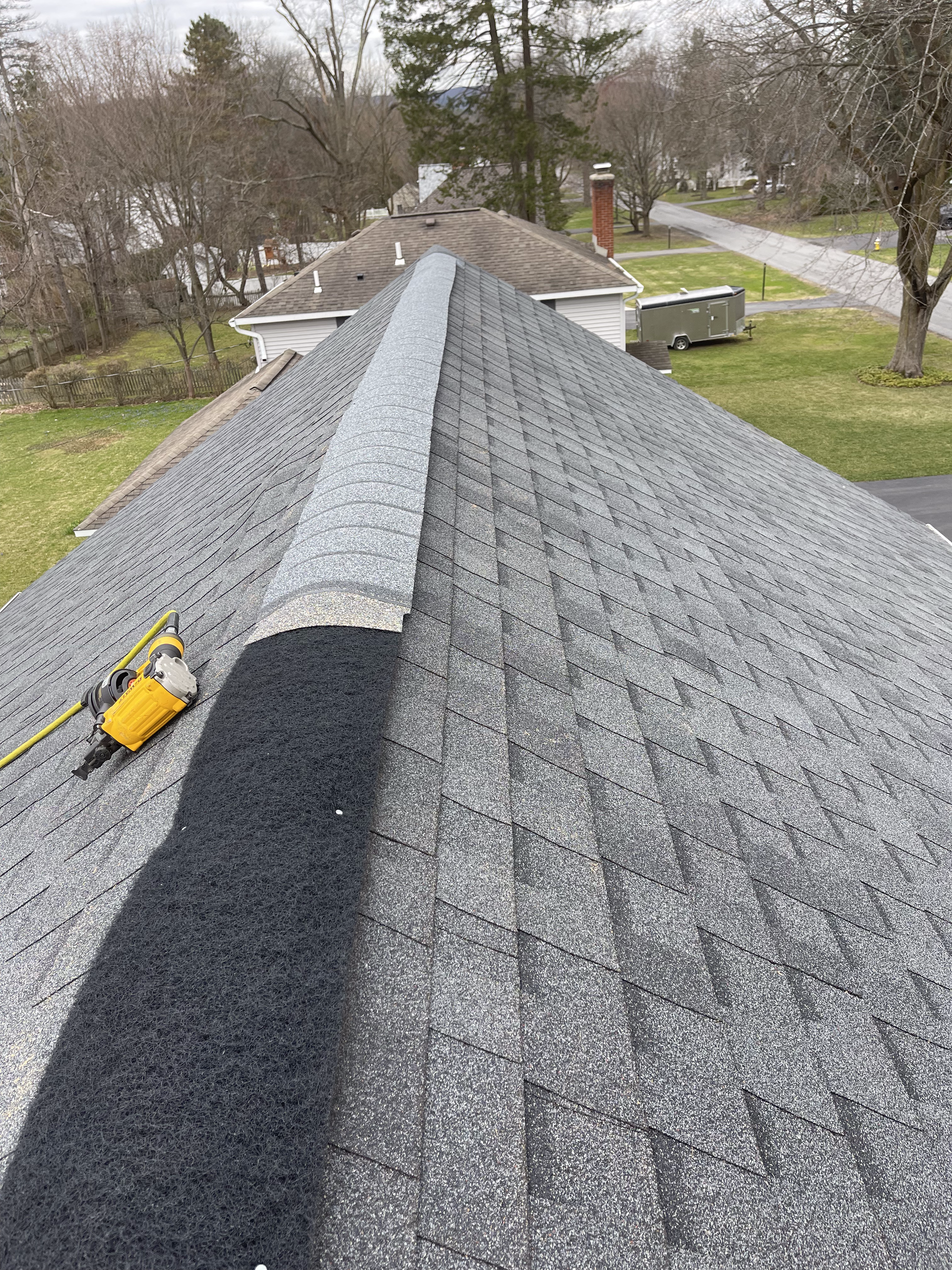 A roof with shingles being installed and a tape measure on it.