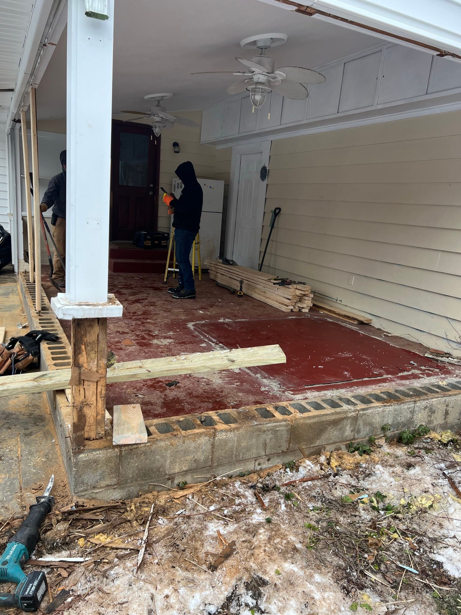 A man is working on a porch of a house.