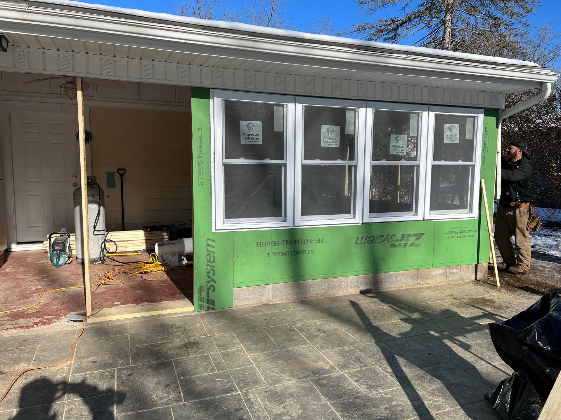 A man is standing in front of a house that is being remodeled.