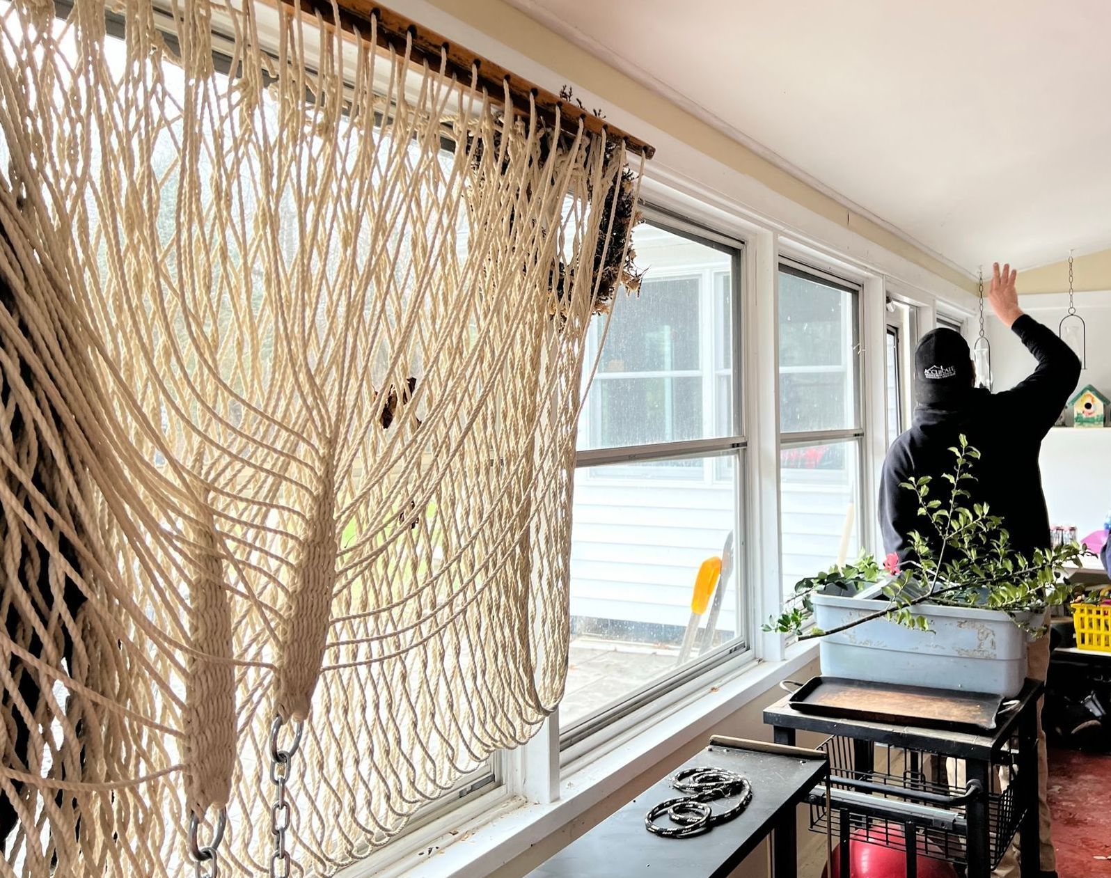 Two men are standing in front of a window in a room.