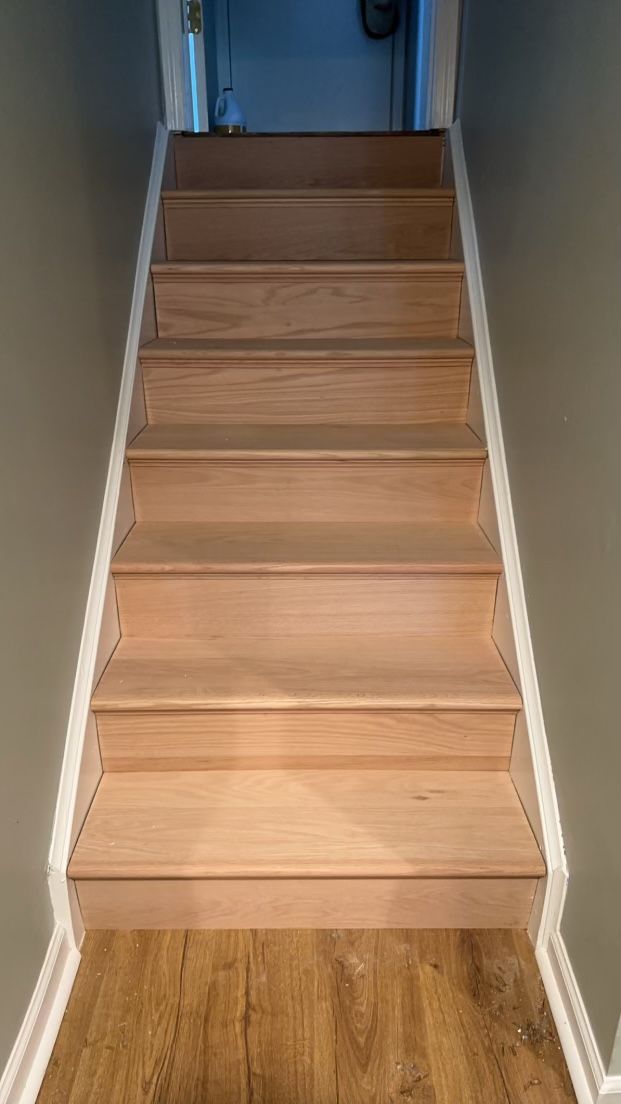 A set of wooden stairs leading up to a hallway in a house.