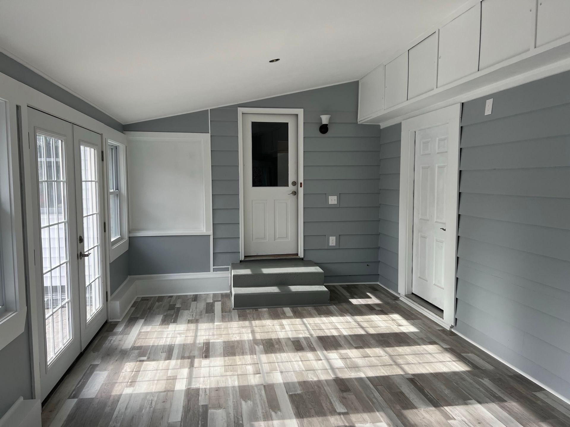 An empty room with a wooden floor and a white door.