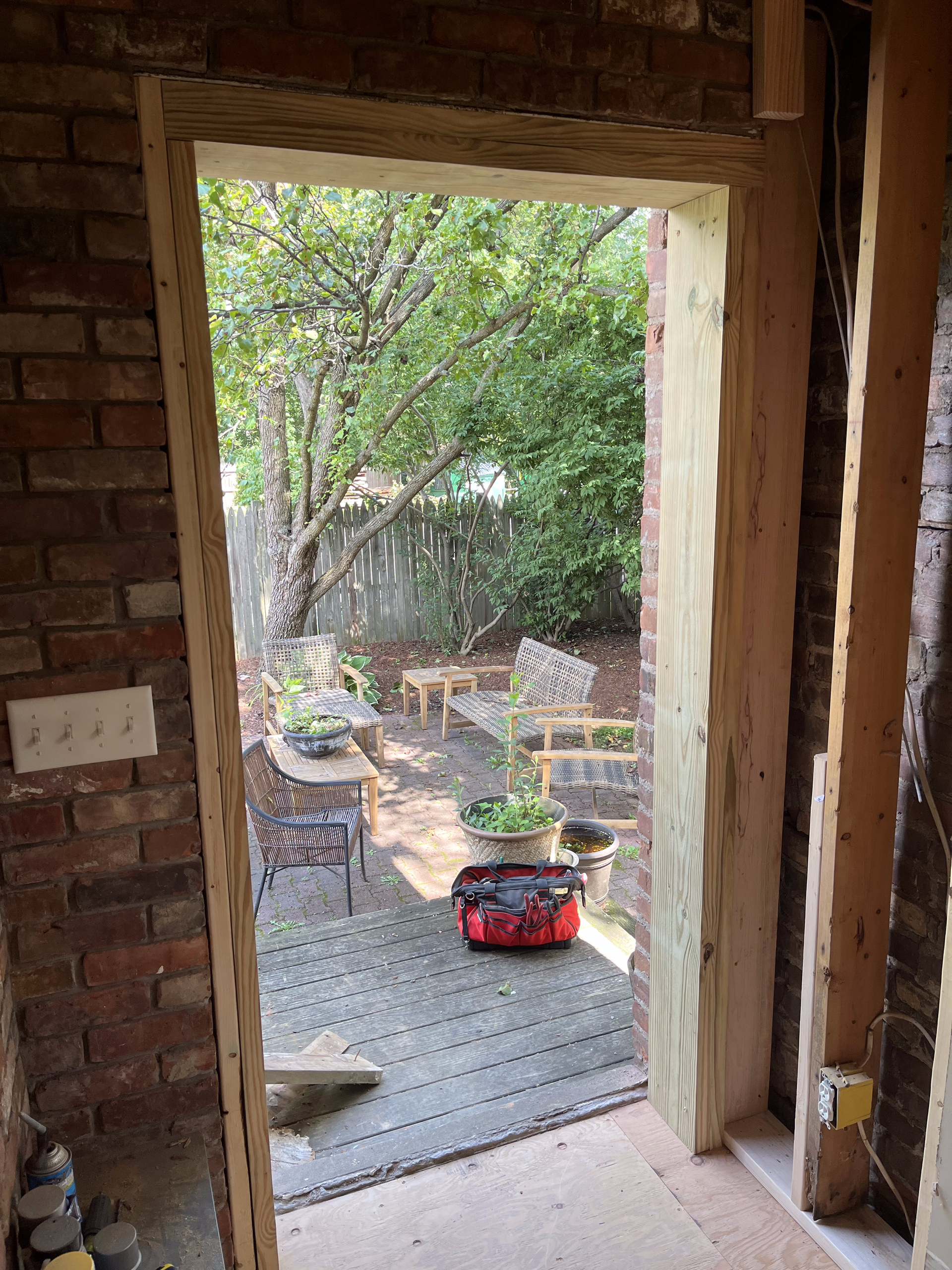 A view of a backyard through a doorway in a brick building.
