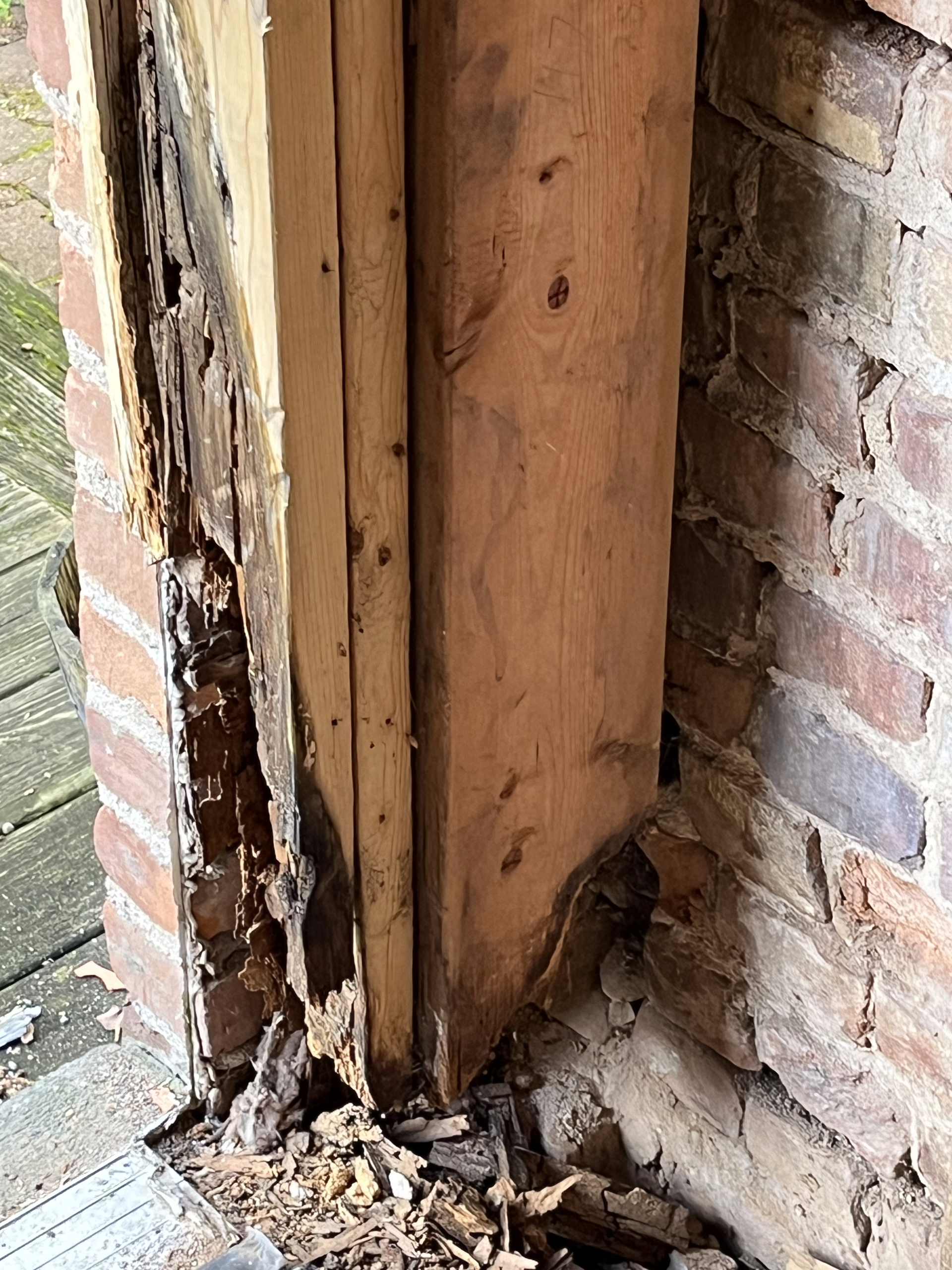 A brick wall with a piece of wood missing from it.