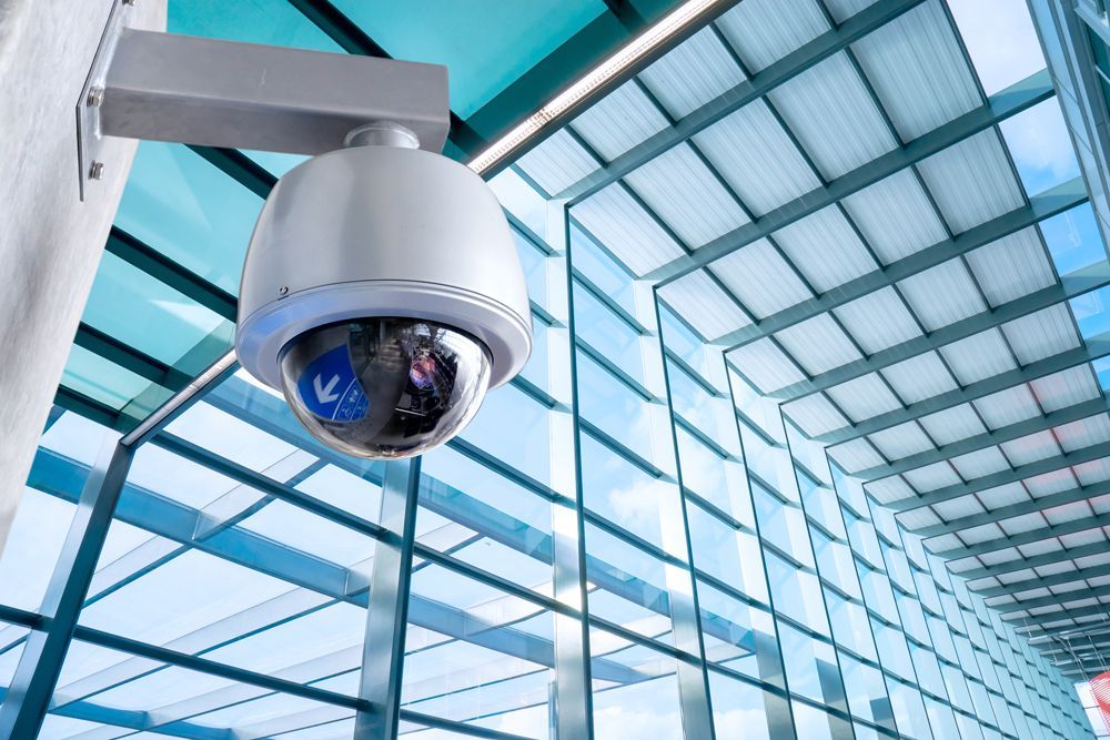 A security camera is hanging from the ceiling of a building.